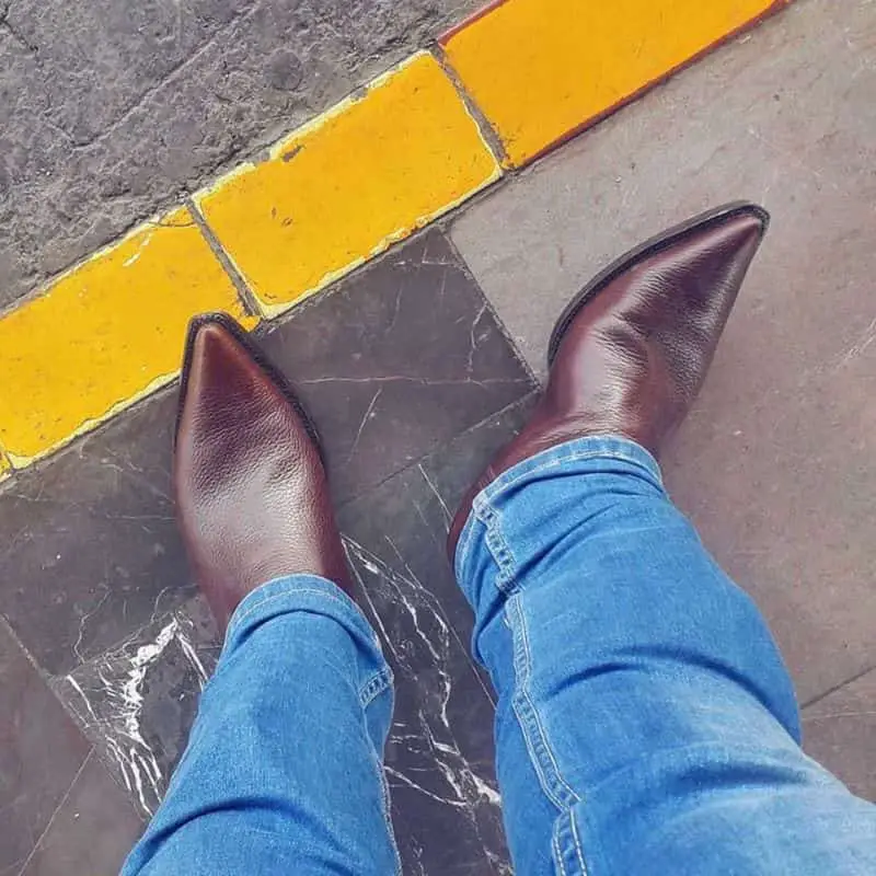 A man wears cowboy boots and is standing