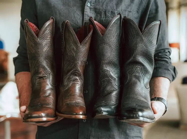 Man holding 2 pairs of chisos boots