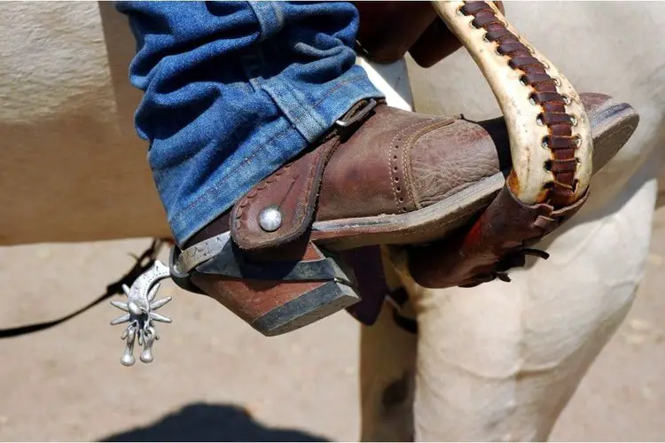 Man wears cowboy cut jeans and riding horse