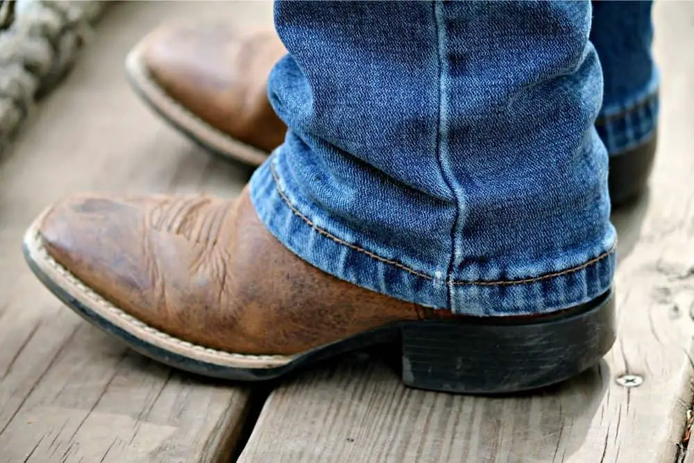 A man wears jeans with broad square toe cowboy boots