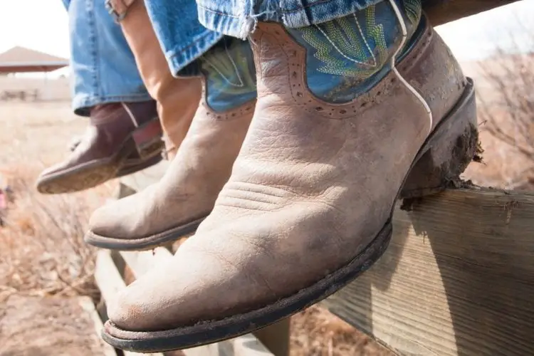 men wear cowboy boots sit on the fence