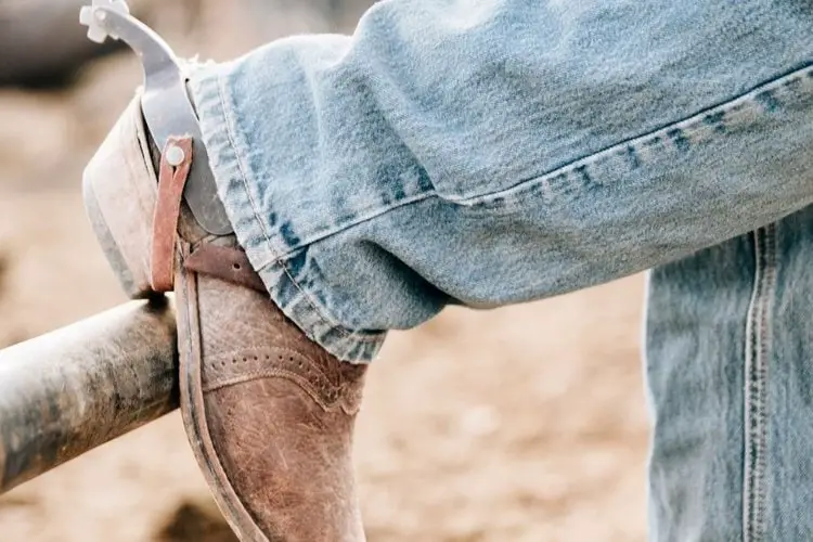 men wear jeans with cowboy boots put his leg on the wood fence