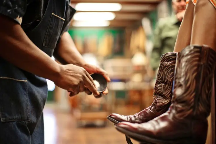 man is polishing cowboy boots with stitching