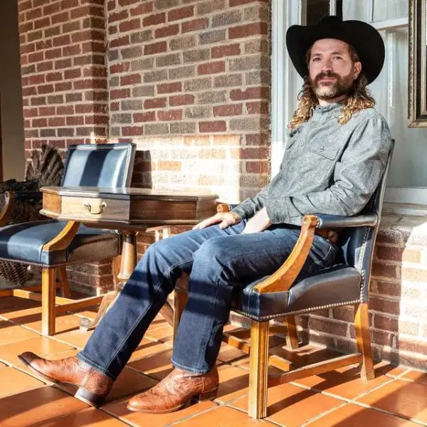 A men wears Tecovas flannel shirt with jeans and brown cowboy boots