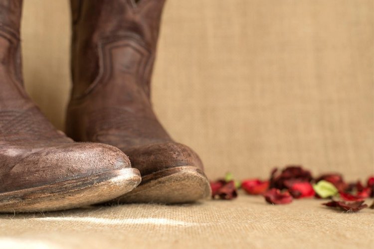 Cowboy boots are scuffed at toe