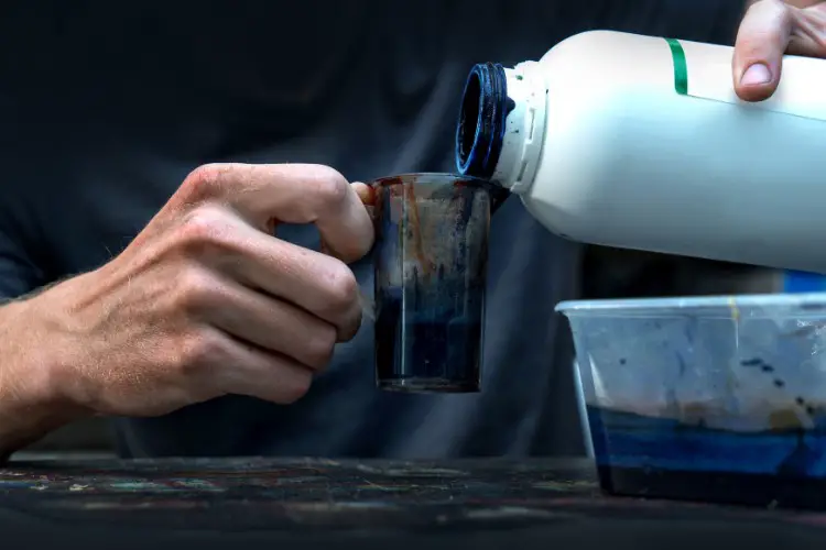 A man is pouring leather dye into container box