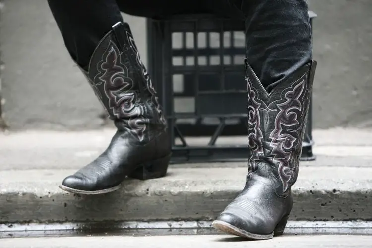 A man wears black cowboy boots