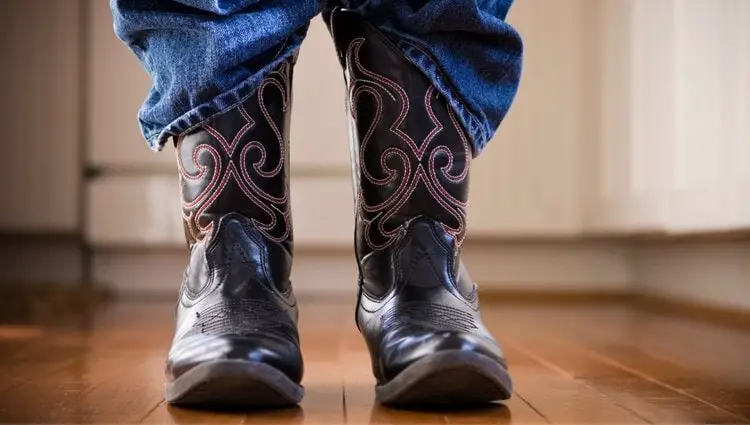A man wears cowboy boots and stand on the floor