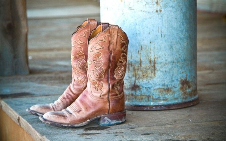 a pair of muddy cowboy boots on the wood floor