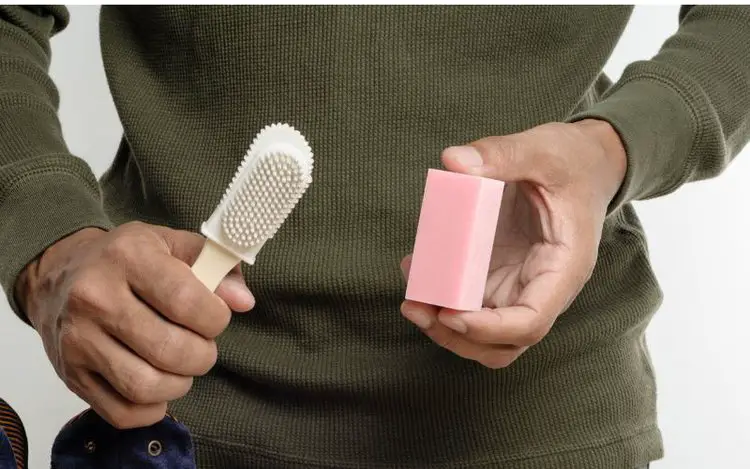 A man is holding suede eraser and suede brush