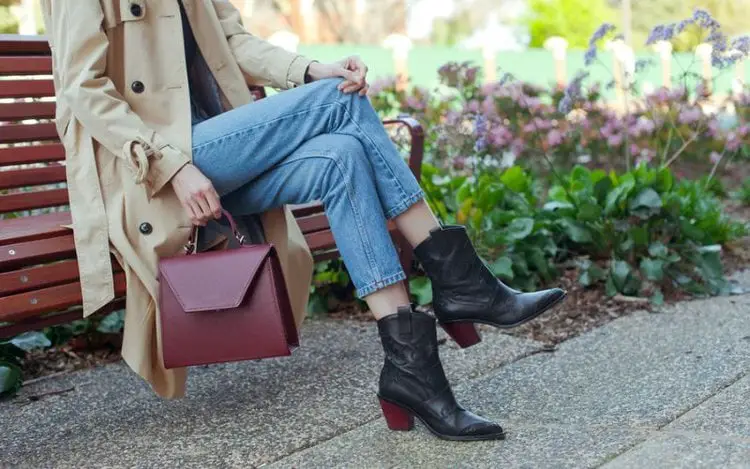 A woman wear jeans with black cowboy boots and a blazer