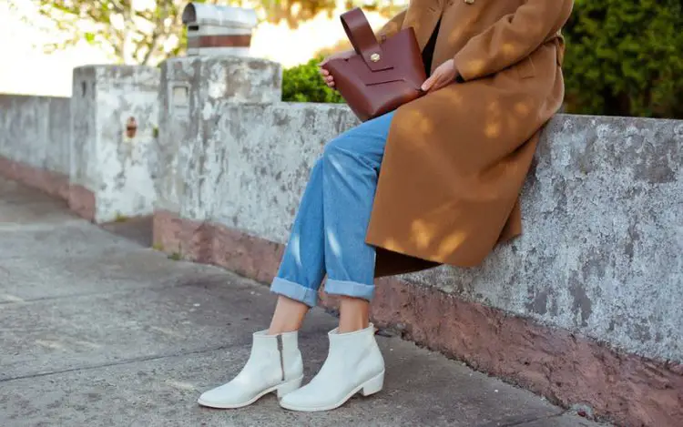 A woman wears ankle cowboy boots with jeans and a blazer