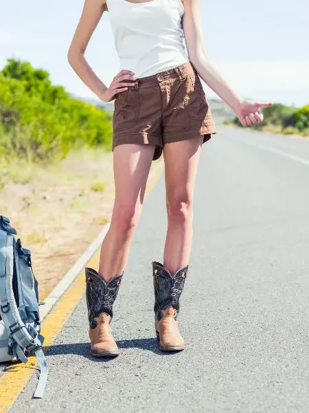 A woman wears cowboy boots on the road in the summer