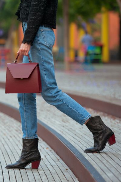 A woman wears jeans with cowboy boots in the city