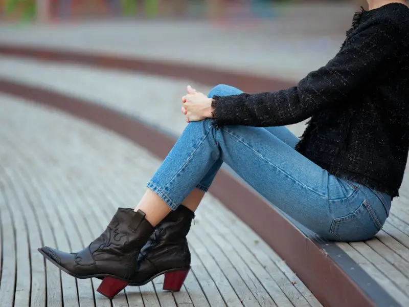 A woman wears jeans with cowboy boots