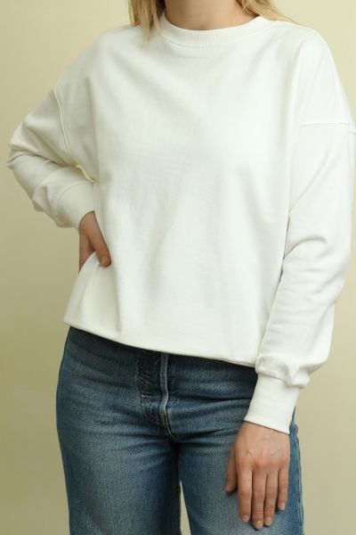 Woman wears white sweater with jeans