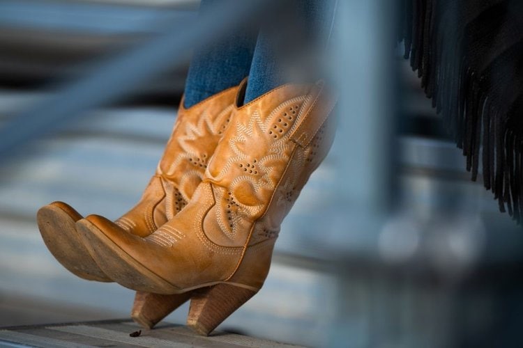 A woman wears a pair of fashion cowboy boots.