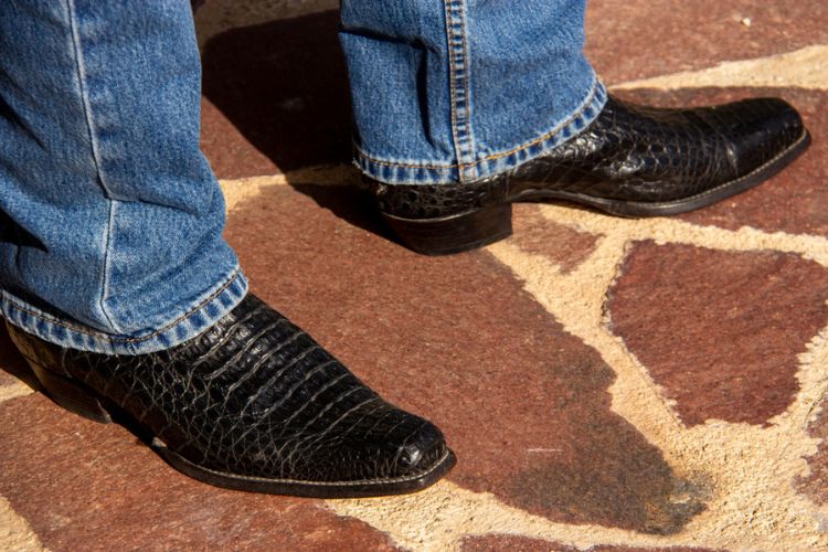 a man wears alligator cowboy boots