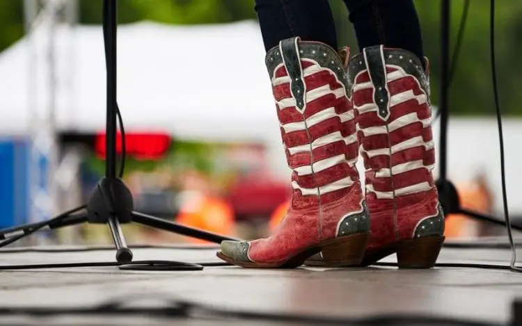 Women wear cowboy boots and jeans and are singing