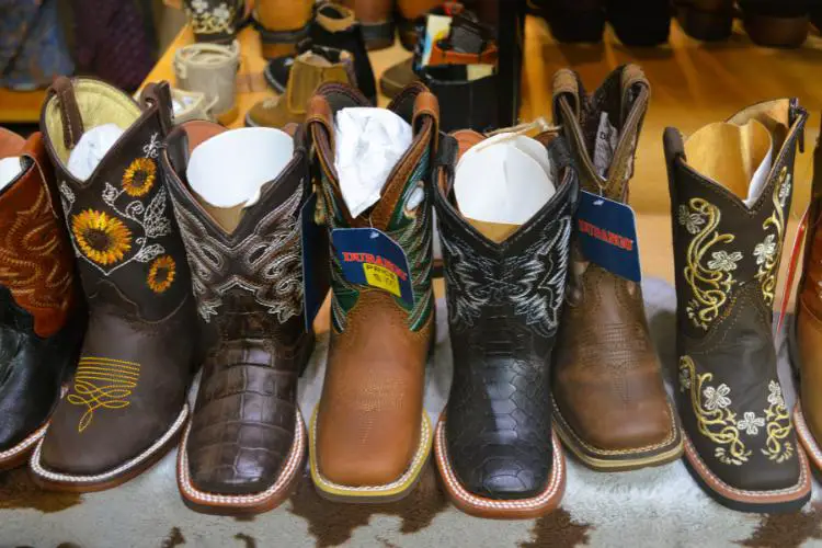 Many cowboy boots are standing upright