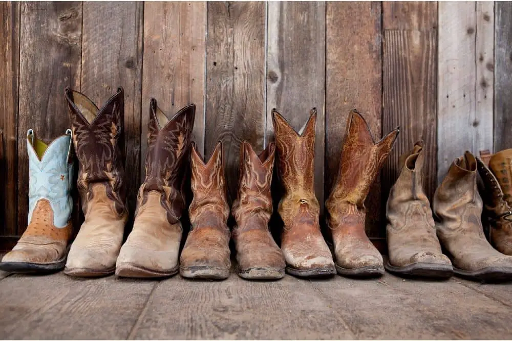 Many pair of cowboy boots on the wooden floor