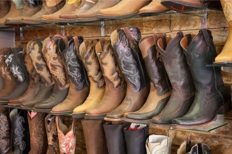 Many pair of cowboy boots on the boot stand