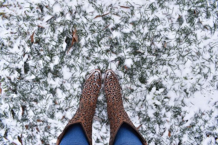 A woman is wearing cowboy boots in the snow