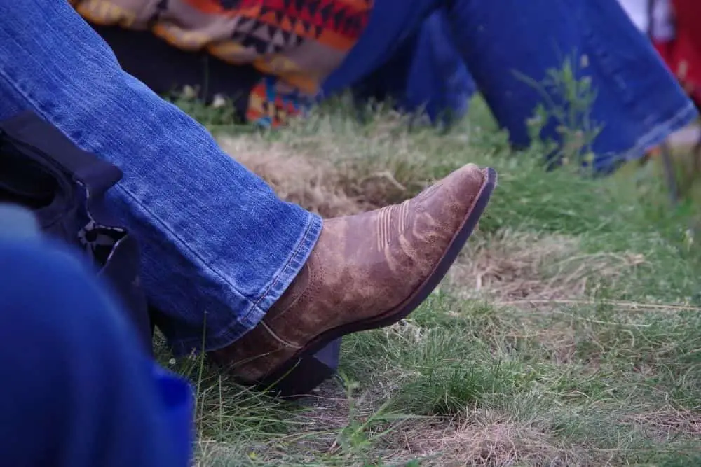 men wear jeans and cowboy boots hiking on a mountain