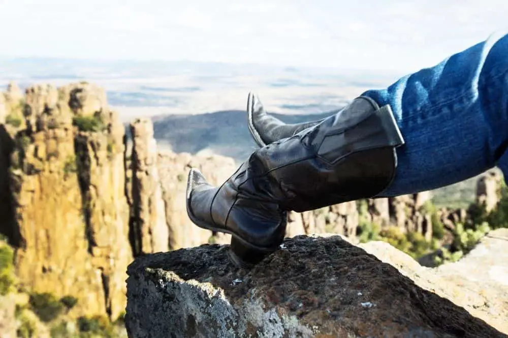 wearing jeans with black pointed toe cowboy boots hiking on rocky mountain