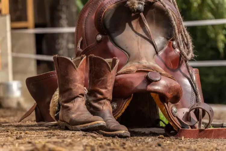 A pair of cowboy boots and saddle on the ranch