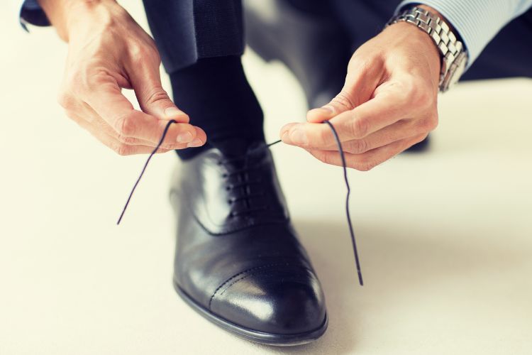 a man is tying dress shoes