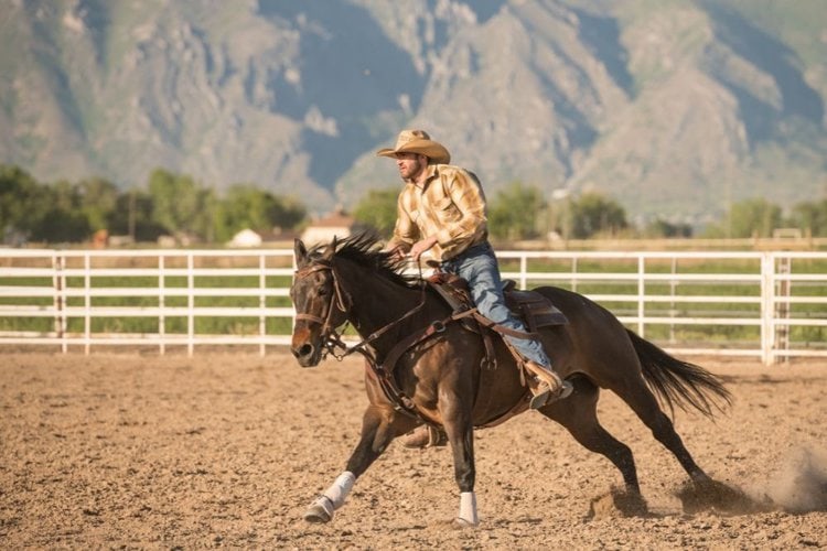 cowboy wearing cowboy boots riding a black horse