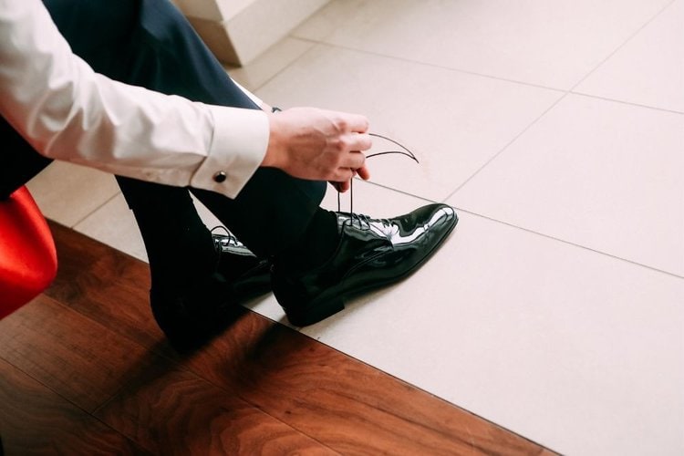 man tie the laces of his black dress shoes