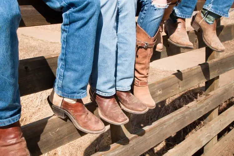 Mans wear cowboy boots sit on the fence