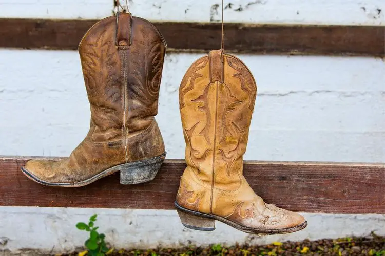 Old cowboy boots hooked int he wood fence