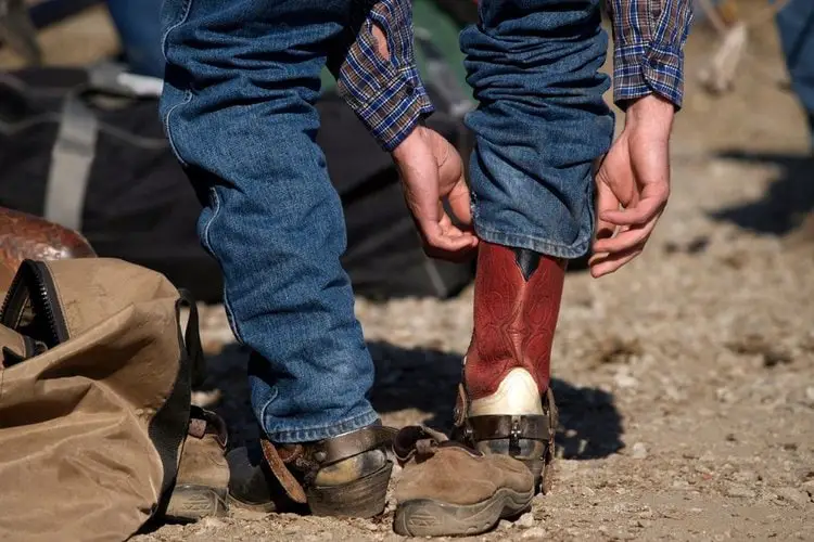 A man tuck cowboy boots into boot cut jeans