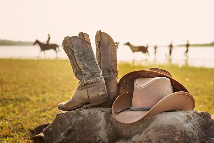 Cowboy boots and cowboy hat on the rock of the farm