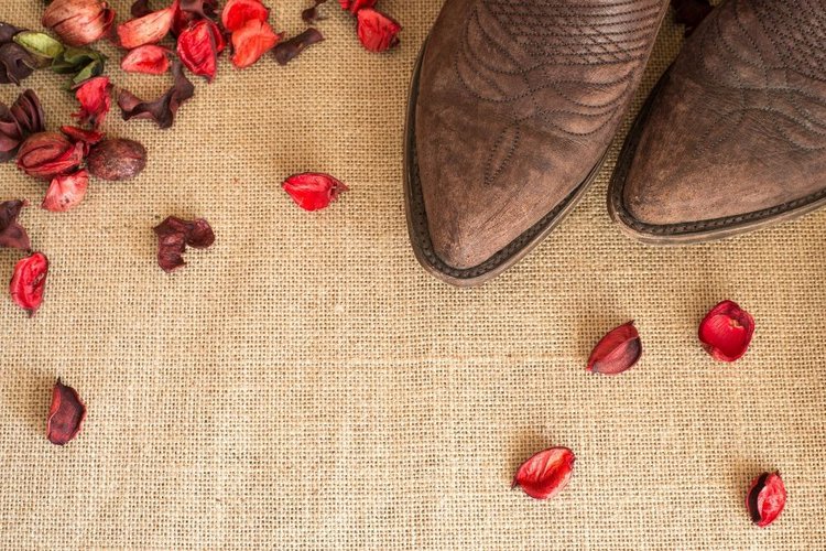 Cowboy boots with dried rose on the ground