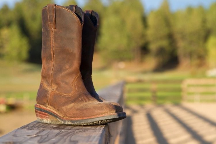 a pair of cowboy boots on the wooden fence