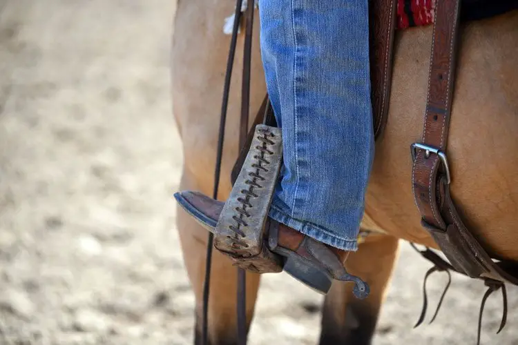 man wearing jeans and cowboy boots riding a horse