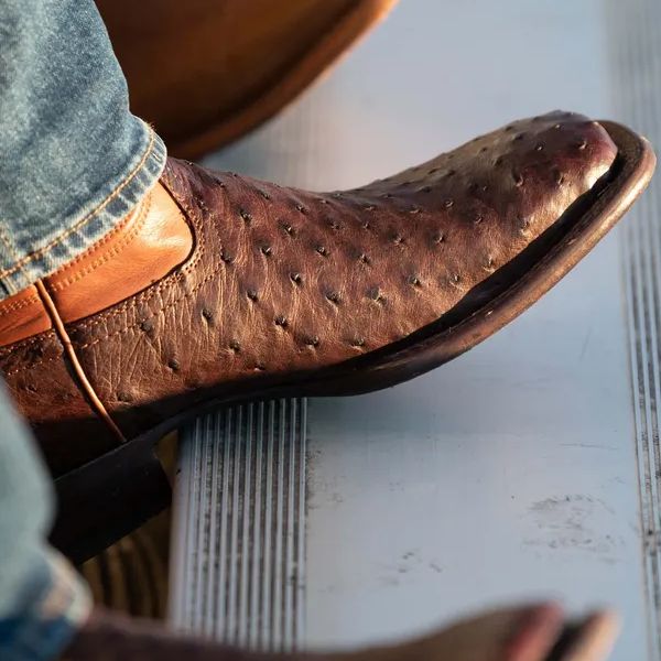 A man wears Emmitt Cowboy boots with jeans and is sitting