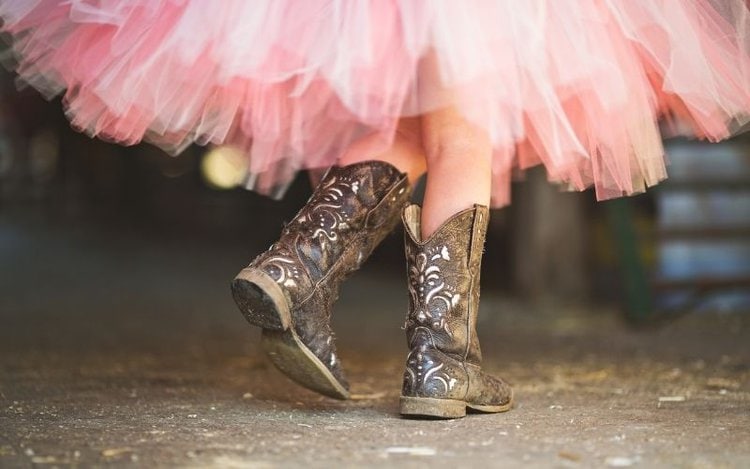 Girl wear cowboy boots with pink skirt