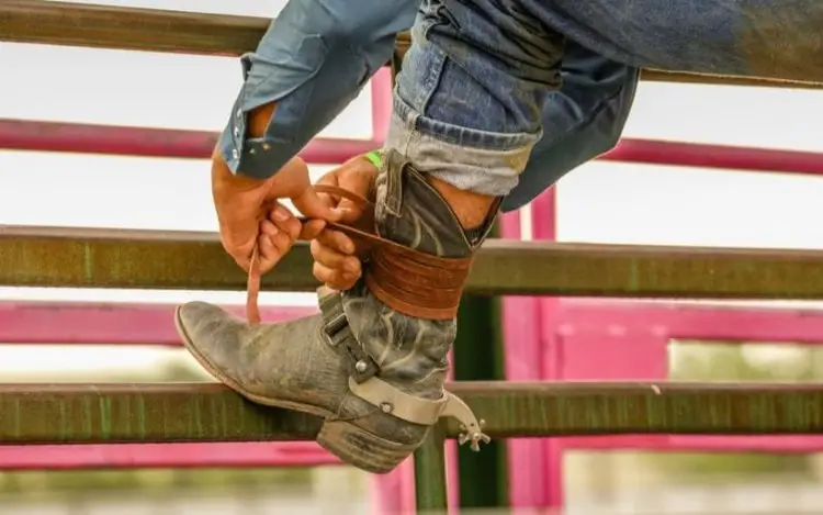 Man tighten his cowboy boots with leather lace