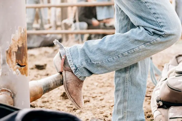 Man wear fade jeans with cowboy boots stand on the fence