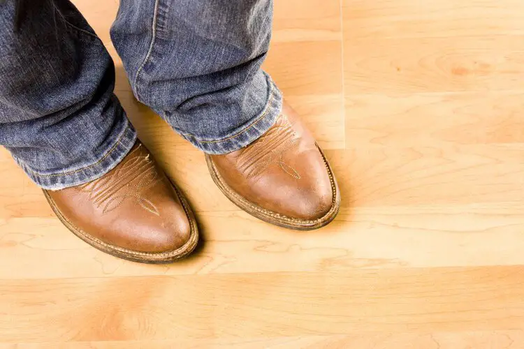 Man wear round toe cowboy boots stand on wooden floor