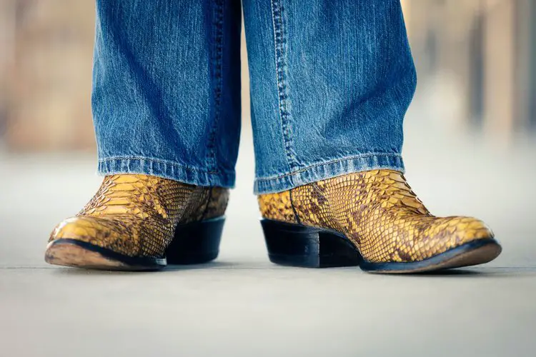Men wear snakeskin cowboy boots and jeans stand on the floor