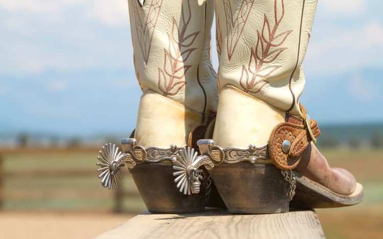 A pair of cowboy boots on the wooden under the sky