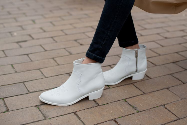 A woman wears black legging with white cowboy boots