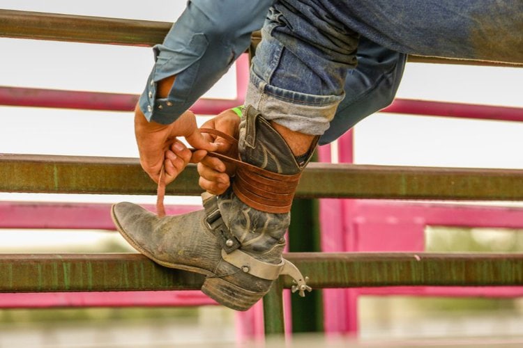 Man tighten his cowboy boots with leather string