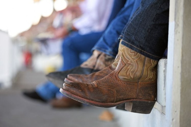 Man wear cowboy boots with jeans and sitting down
